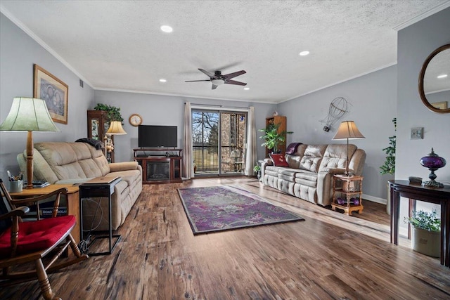 living area featuring ornamental molding, a textured ceiling, wood finished floors, a fireplace, and ceiling fan