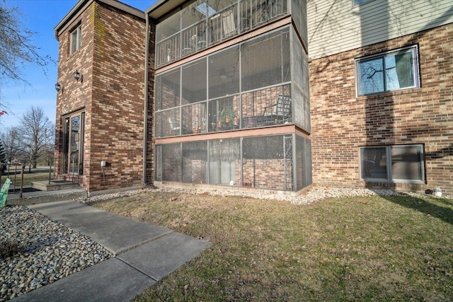 view of home's exterior with a yard, brick siding, and a sunroom