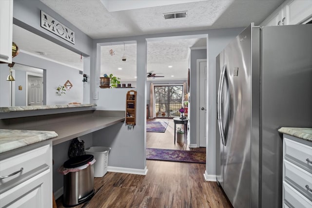 kitchen with visible vents, white cabinetry, a textured ceiling, and freestanding refrigerator