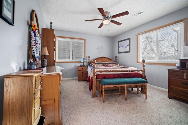 bedroom featuring visible vents, light colored carpet, a textured ceiling, and baseboards