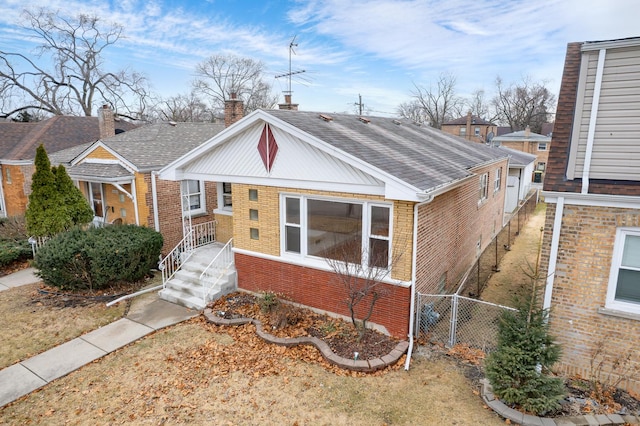 bungalow-style home featuring a shingled roof, fence, brick siding, and a chimney