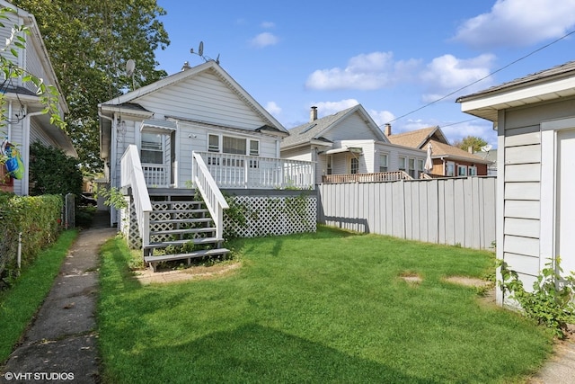 rear view of property with a lawn, a deck, and fence