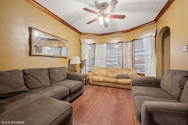 living area with ceiling fan, arched walkways, wood finished floors, and ornamental molding