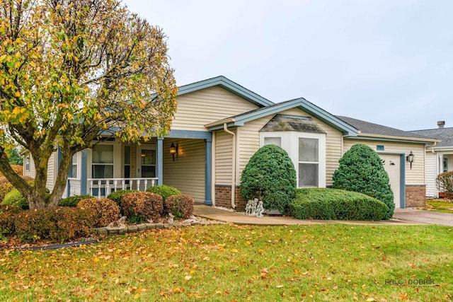 view of front of property with a front yard, driveway, an attached garage, covered porch, and brick siding