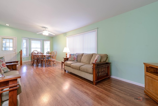 living room featuring baseboards, light wood finished floors, and ceiling fan