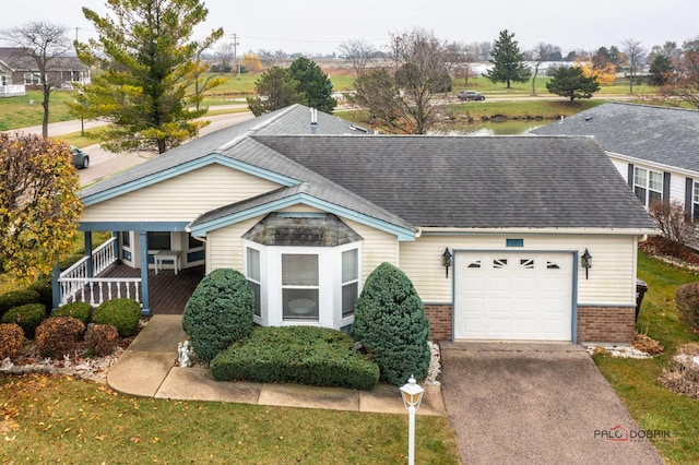 view of front of house with brick siding, driveway, a garage, and roof with shingles