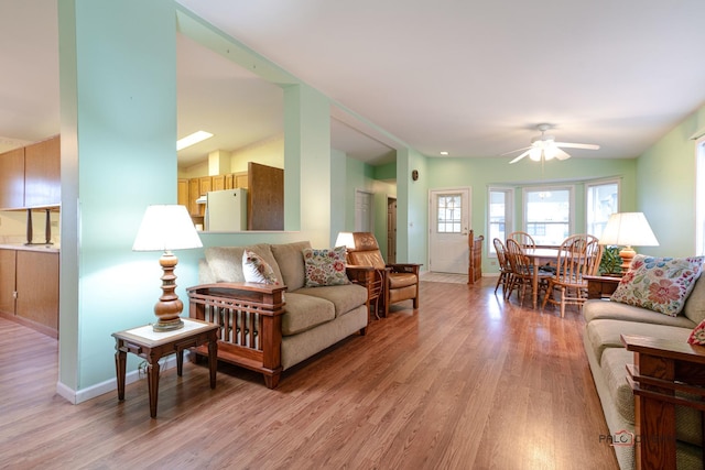 living room featuring light wood-style flooring, baseboards, and ceiling fan