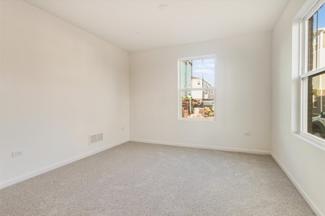 spare room with a wealth of natural light, visible vents, baseboards, and carpet