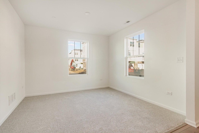 unfurnished room with baseboards, visible vents, light carpet, and a healthy amount of sunlight