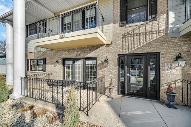 entrance to property with brick siding and a balcony