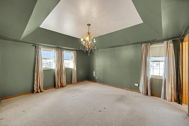 empty room with a healthy amount of sunlight, a raised ceiling, baseboards, and carpet floors