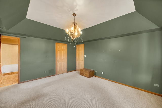 empty room with a notable chandelier, lofted ceiling, carpet, and baseboards