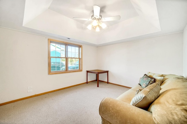 living area with a raised ceiling, carpet flooring, and baseboards