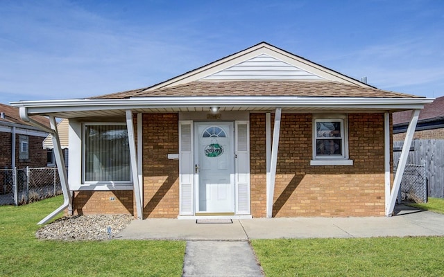 bungalow with covered porch, fence, and brick siding