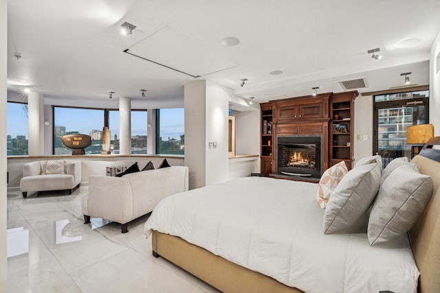 bedroom with visible vents, marble finish floor, and a glass covered fireplace