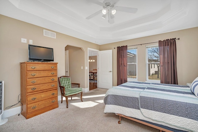 bedroom with visible vents, baseboards, arched walkways, a raised ceiling, and light colored carpet