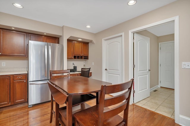 kitchen with light wood finished floors, recessed lighting, brown cabinets, and freestanding refrigerator