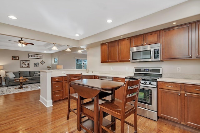 kitchen featuring light wood-style floors, appliances with stainless steel finishes, a peninsula, and light countertops