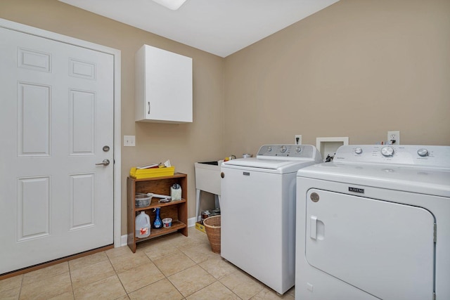 washroom featuring cabinet space, washing machine and dryer, baseboards, and light tile patterned flooring