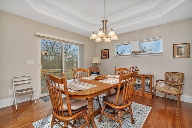 dining space featuring a wealth of natural light, a raised ceiling, and light wood-style flooring