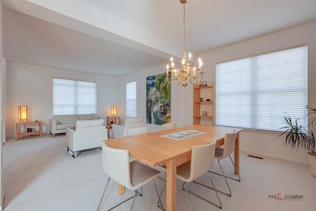 dining room with baseboards, light colored carpet, visible vents, and a chandelier