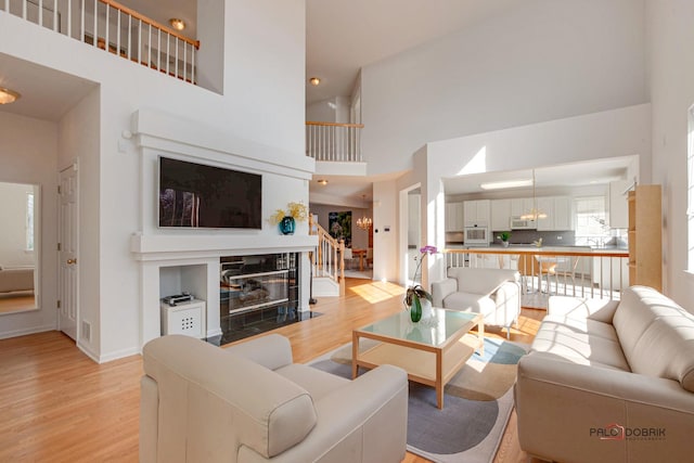 living room featuring light wood finished floors, a fireplace, stairs, and baseboards