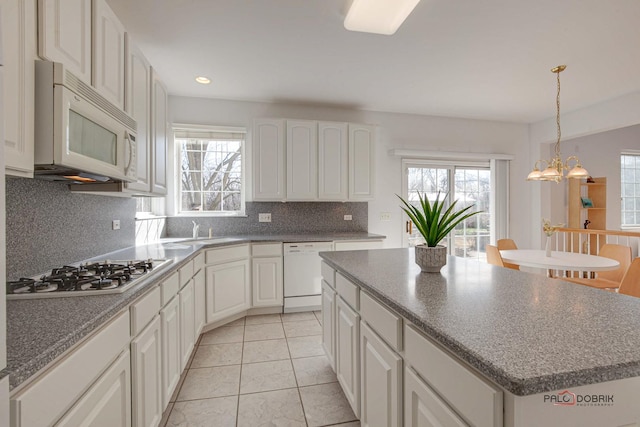 kitchen featuring decorative backsplash, white appliances, plenty of natural light, and a center island