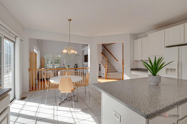 dining space with a chandelier, stairs, and light tile patterned flooring