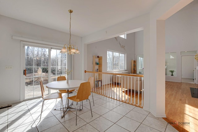 dining room featuring a chandelier, light tile patterned floors, baseboards, and vaulted ceiling