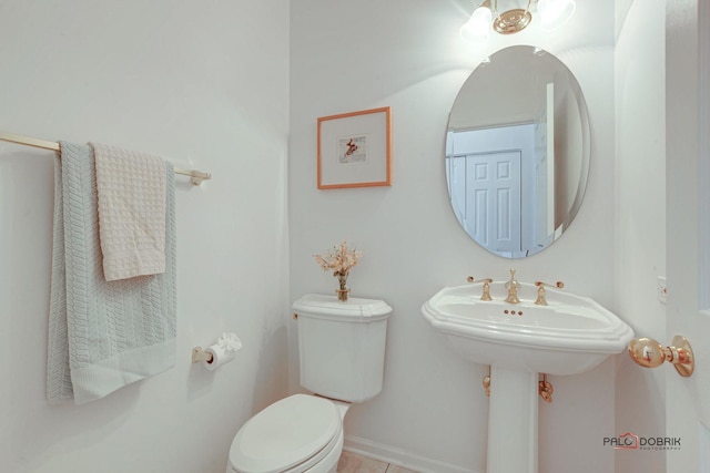 half bath featuring tile patterned floors, toilet, and baseboards