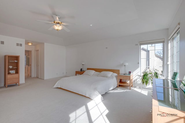 bedroom featuring a tray ceiling, visible vents, light colored carpet, and a ceiling fan