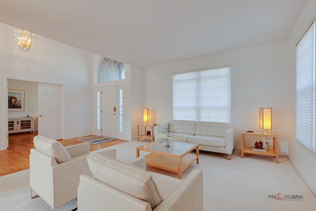 living area with baseboards, light wood-style floors, and an inviting chandelier