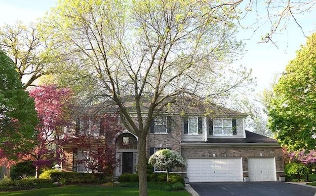 view of front of property with aphalt driveway, an attached garage, and a front lawn