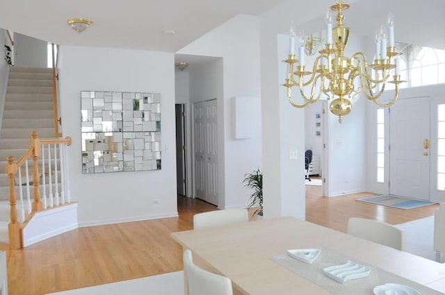 dining room with stairway, wood finished floors, and a chandelier