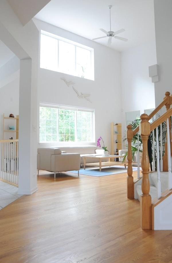 interior space featuring stairway, a high ceiling, wood finished floors, and a ceiling fan