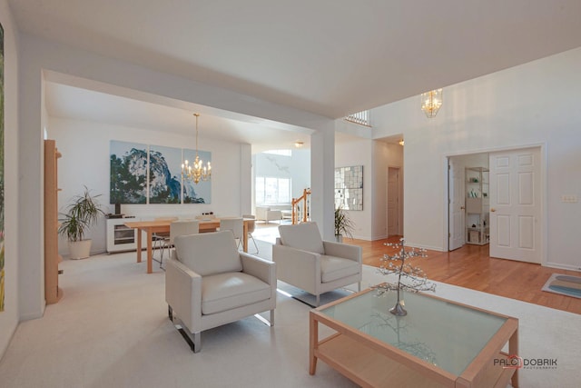 living room featuring a notable chandelier, baseboards, and light wood-type flooring