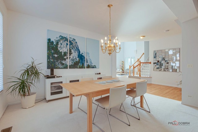 dining area featuring a notable chandelier, visible vents, stairway, and baseboards