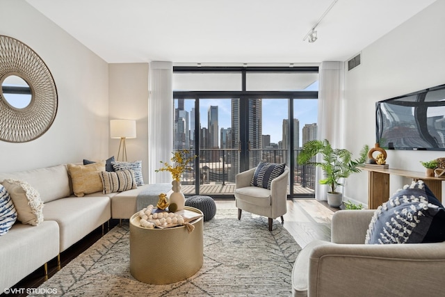 living room with visible vents, wood finished floors, rail lighting, and expansive windows