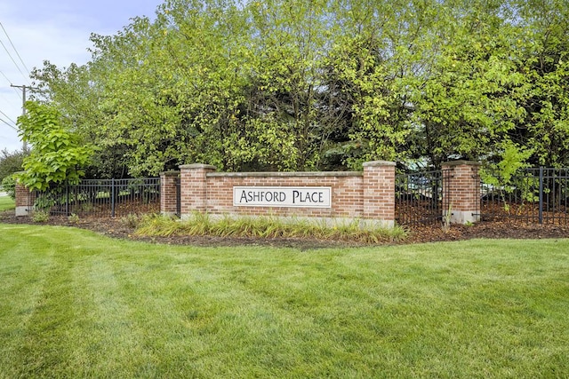 community / neighborhood sign featuring a lawn and fence