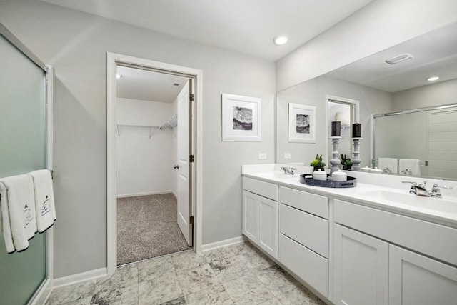 full bath featuring double vanity, a spacious closet, a stall shower, and a sink