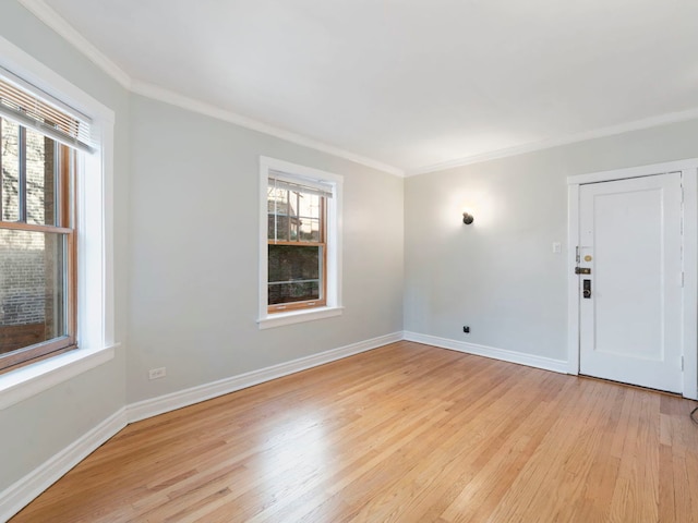 unfurnished room featuring light wood finished floors, plenty of natural light, crown molding, and baseboards