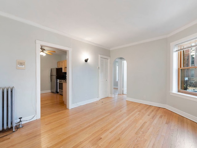 unfurnished room with radiator, crown molding, baseboards, light wood-style floors, and arched walkways