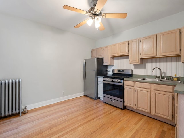 kitchen featuring light brown cabinetry, radiator, stainless steel appliances, and a sink