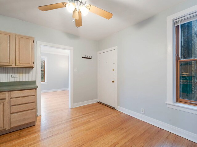 interior space with light wood-style flooring, a ceiling fan, and baseboards