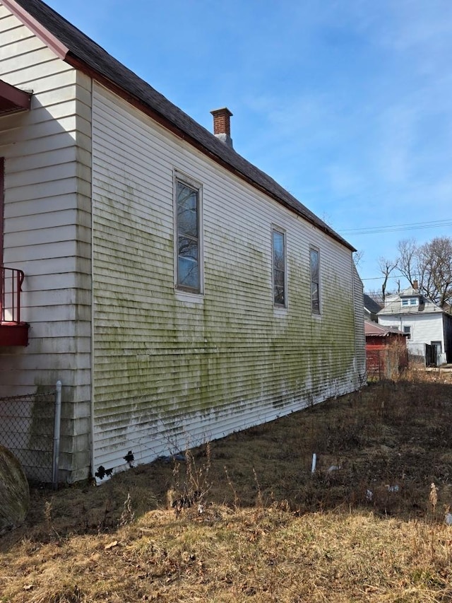 view of home's exterior featuring central air condition unit, fence, and a chimney