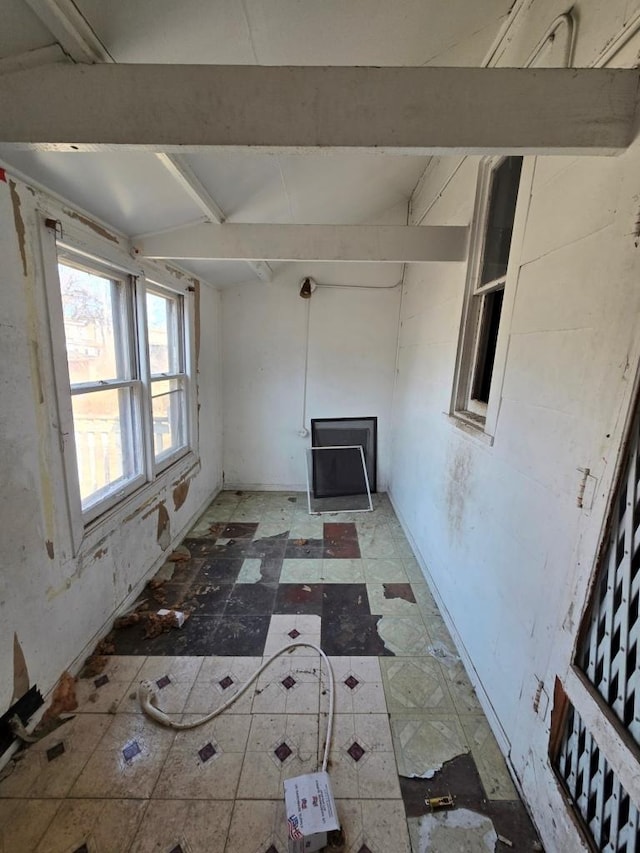 unfurnished living room featuring beam ceiling and light floors