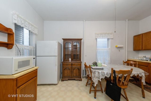 kitchen with light floors, white appliances, light countertops, and brown cabinets