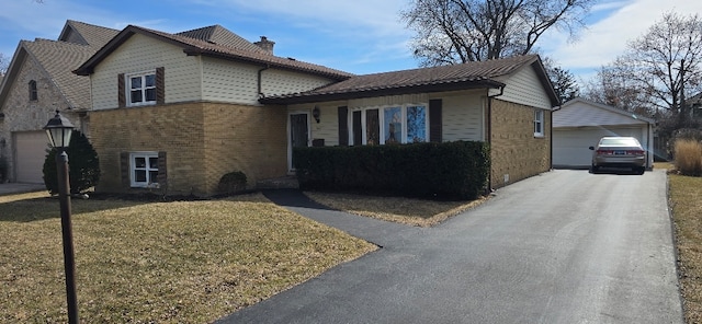 tri-level home featuring a front lawn, brick siding, an outdoor structure, and a chimney