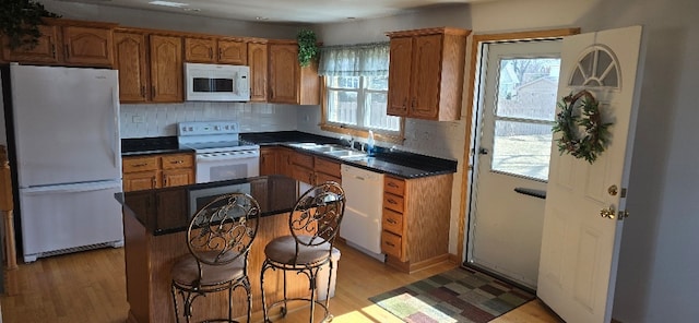 kitchen with a sink, light wood-type flooring, white appliances, and a wealth of natural light