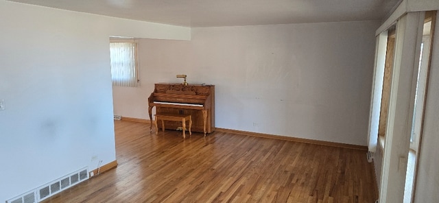 empty room with visible vents, baseboards, and wood finished floors